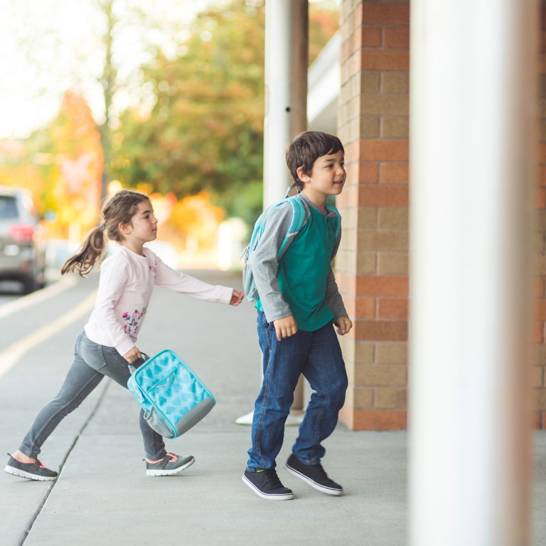 Young boy and girl walking into preschool