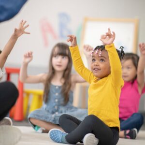 a little girl raising her hands in class