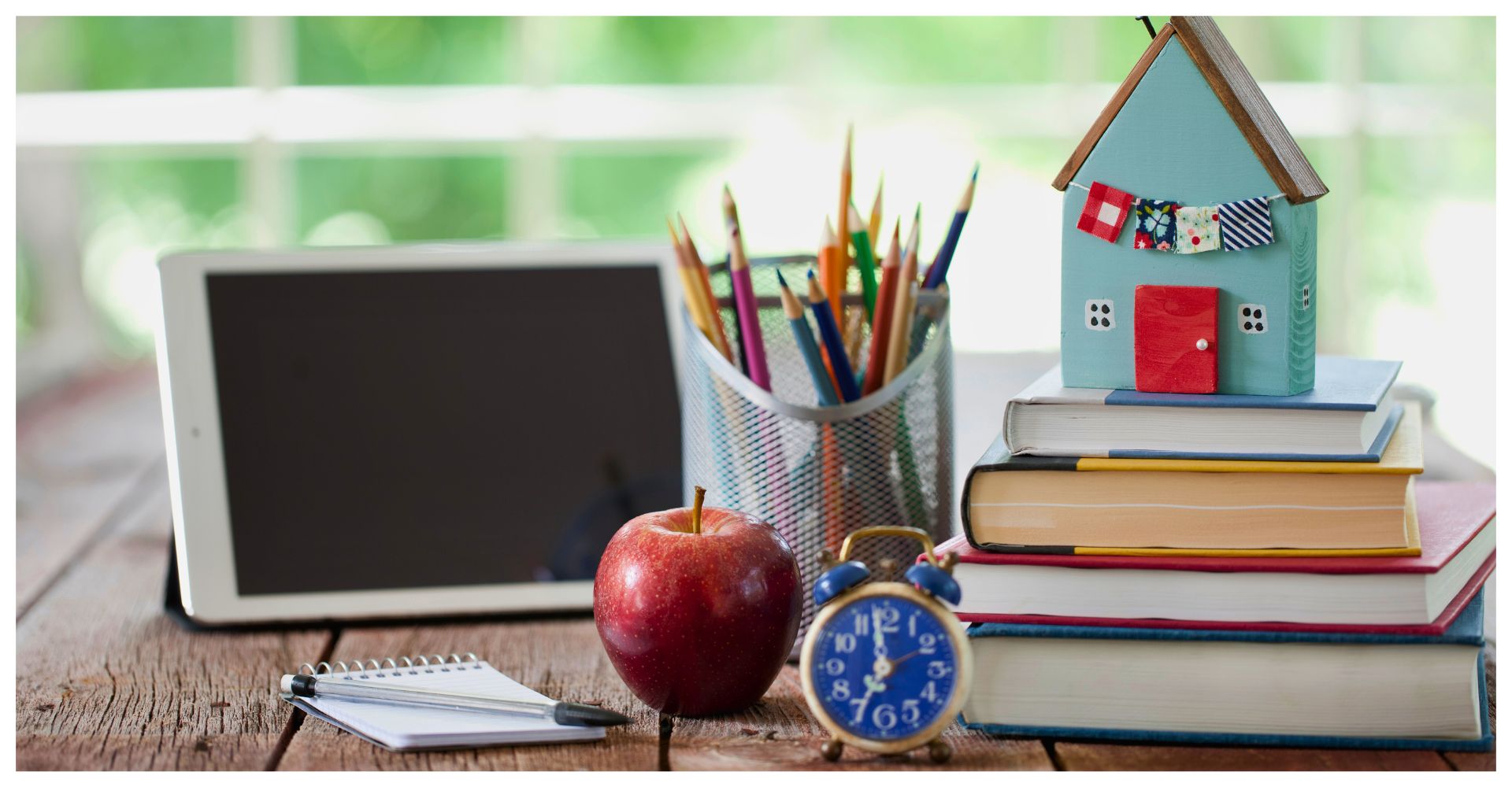 School supplies and a toy house on a table.