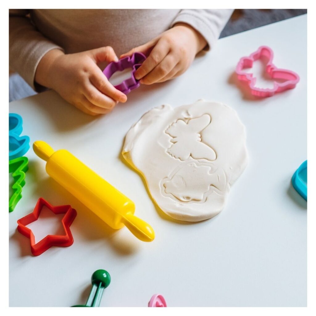 Child playing with playdough and cookie cutters.